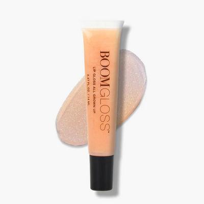 One peach plastic tube of BOOMGLOSS LIP GLOSS ALL GROWN UP 0.47 FL. OZ. / 14 ML with a shimmering smear behind it.